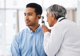 A physician performing an ear examination on a patient.