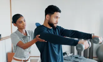 A physical therapist helping a patient with dumbbell exercises.